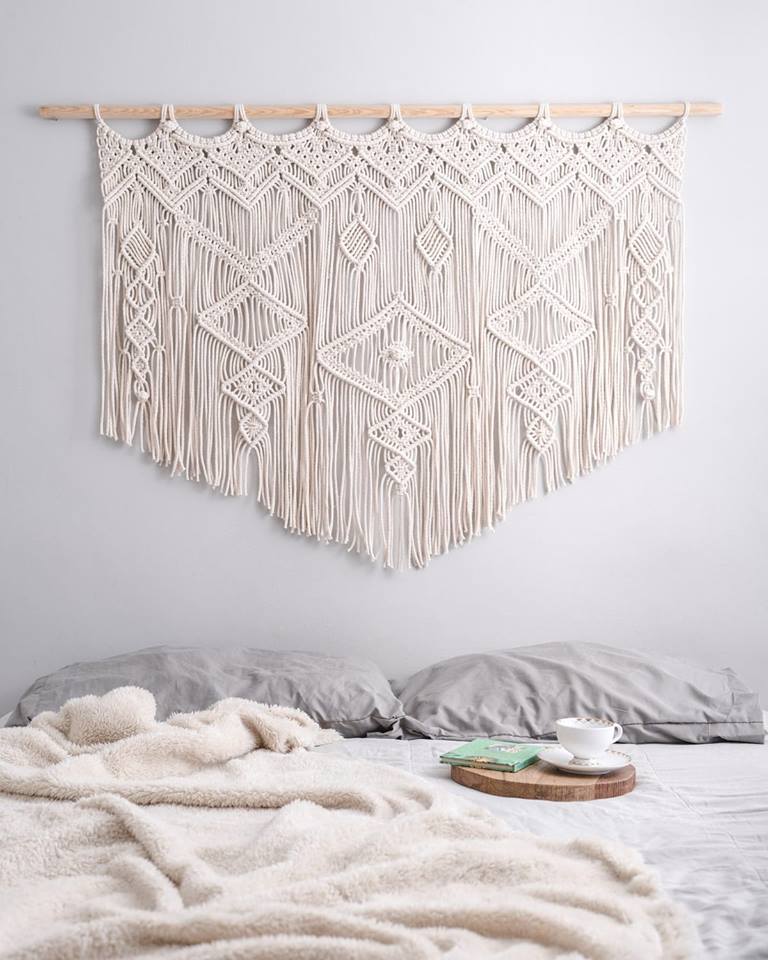 Cama destendida con macramé como cabecera