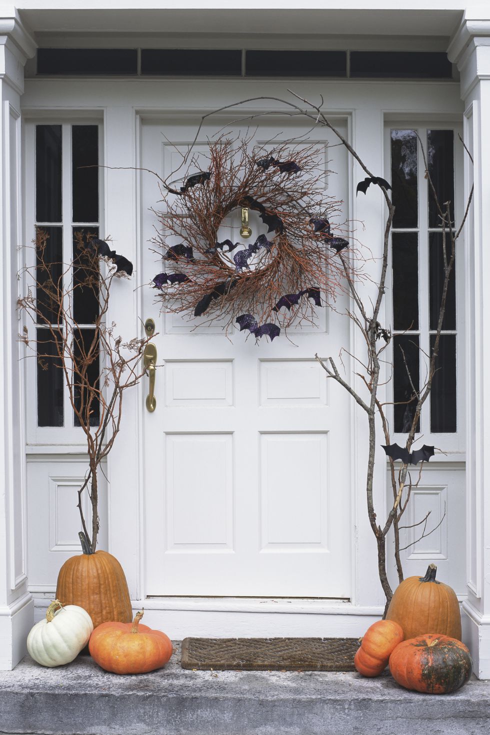 Puerta decorada con corona de halloween, murciélagos y calabazas