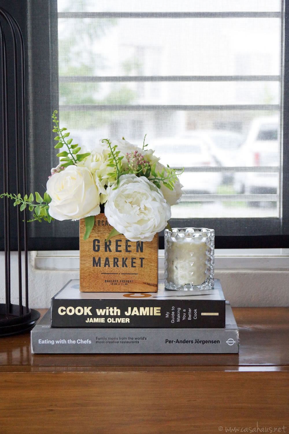 Detalle de libros, flores y vela sobre la credenza