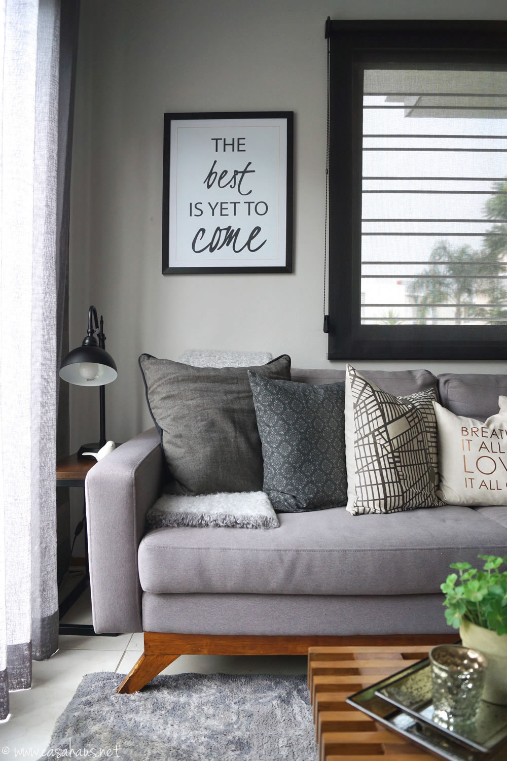 Rincón con sofá gris estilo nórdico con cojines y mesa lateral con lampara industrial